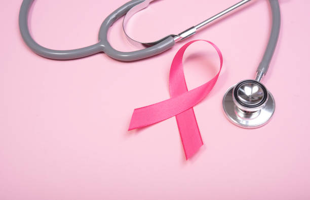 розовая лента рака молочной железы и стетоскоп на розовом фоне. с копировальной площадью - breast cancer pink ribbon alertness стоковые фото и изображения