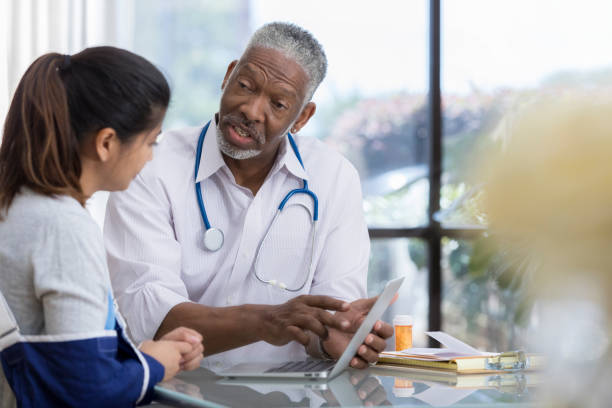 istock Senior male doctor explains symptoms to patient using computer 1034421458