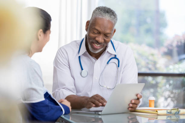 istock Senior male doctor uses computer to explain diagnosis 1034421502