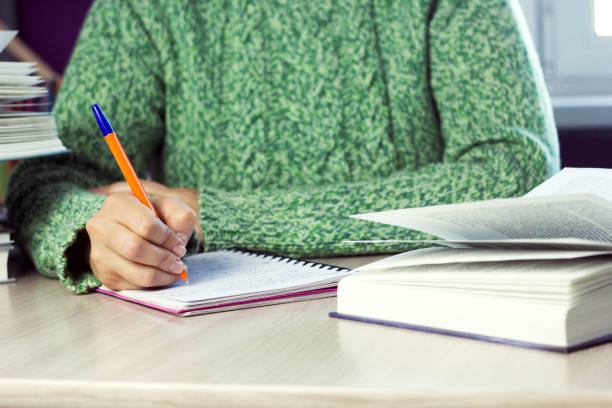 istock woman in  green sweater holding pen,  table with  notebook and  book 1034422054