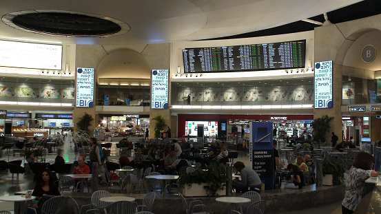 View Of Duty Free Store, Lots Of Passengers Standing, Sitting Down, Looking Around, Eating And Drinking, Talking To One Another While Waiting For Their Flights In Arrival And Departure Hall Of Ben Gurion International Airport In Tel Aviv Israel