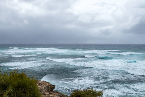 istock Waves crashing on the rocky coastline with dark ominous storm clouds 1034438962