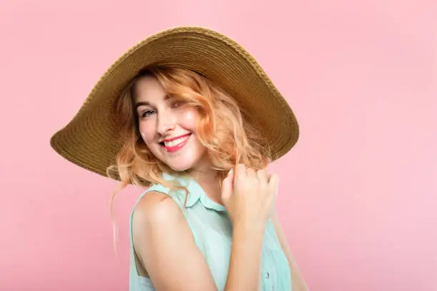 travel agency and tours abroad. summer vacation concept. smiling happy woman in a sunhat. portraitof a young joyful girl on pink background.