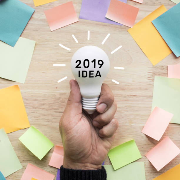 istock 2019 Inspiration ideas concepts with hand holding white lightbulb and colorful notepaper on wood 1034448760