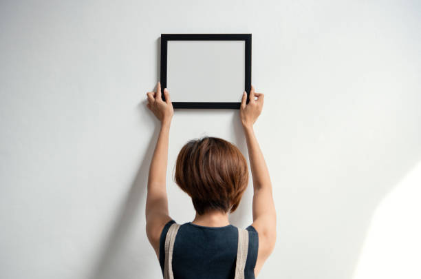 istock Hand Holding Blank Black Photo Frame Hanging Wall for Design Mockup Template. 1034448850