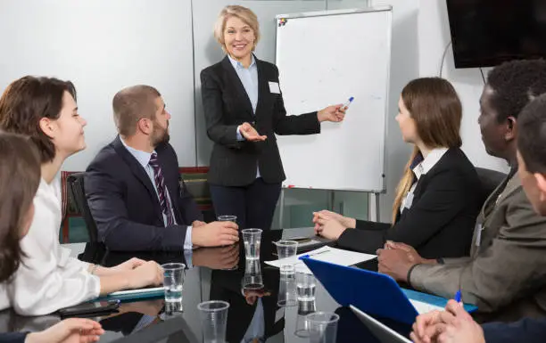 Successful happy senior business woman presenting new business strategy to partners in boardroom