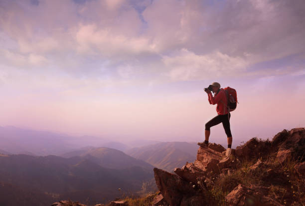 istock Young woman hiker taking photo on mountain peak 1034454872