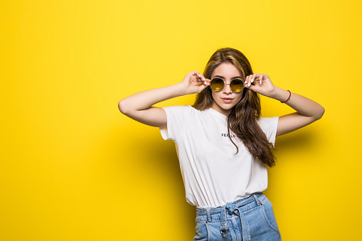 Young woman with sunglasses on a yellow background
