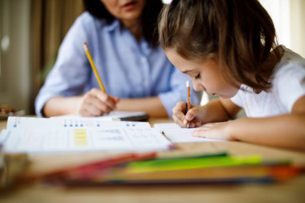 Mother helping daughter with homework stock photo