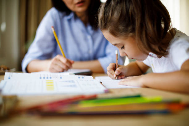 homework time images Mother helping daughter with homework Mother helping daughter with homework homework table stock pictures, royalty-free photos & images
