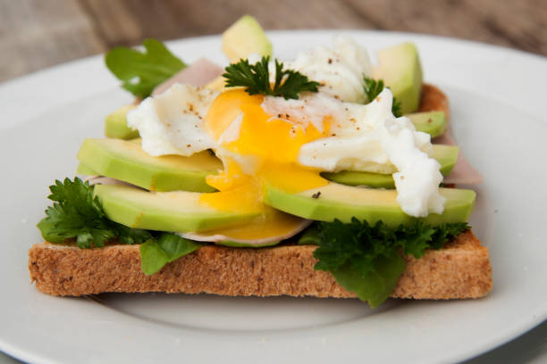 istock Bread toasts with avocado, eggs and greens. Tasty breakfast. Wood background. Isoalted. 1034468558