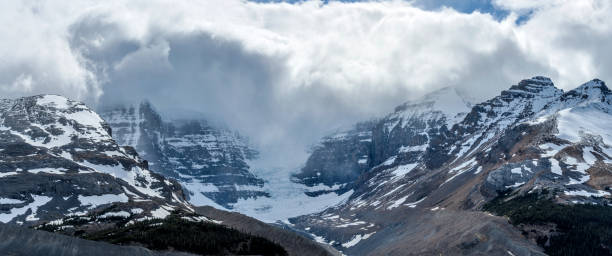 istock Snow Dome Glacier - A panoramic view of thick Spring clouds hanging over Dome Glacier and its surrounding high peaks at Jasper National Park, Alberta, Canada. 1034490484
