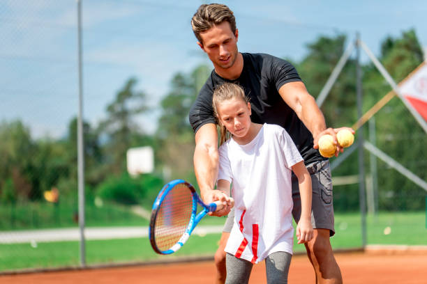 istock Young man teaching a girl playing tennis 1034516436