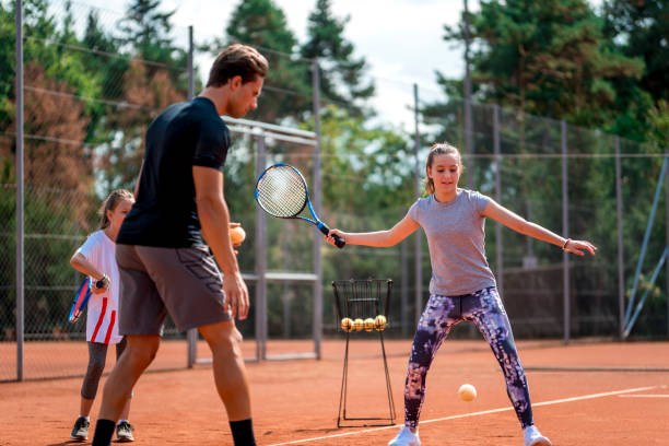 istock Young man teaching a girl playing tennis 1034516444