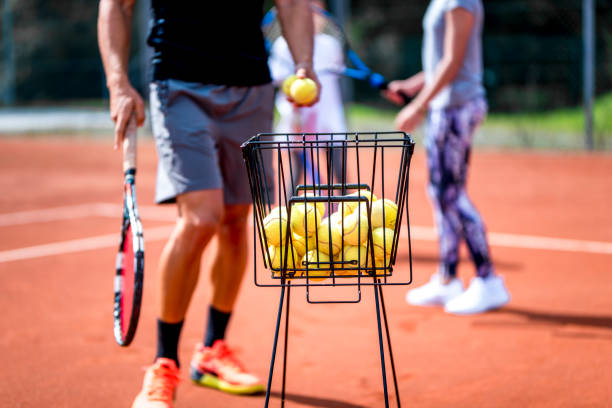 Playing tennis Unrecognizable man holding a racket and a tennis ball by the ball basket. tennis ball container stock pictures, royalty-free photos & images