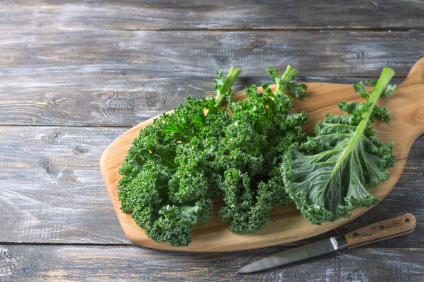 istock Fresh green curly kale leaves on a cutting board on a wooden table 1034529774