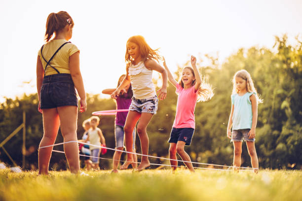 Group of kids playing outdoors jumping the ruber band Group of children playing in public park jumping a ruber band skipping stock pictures, royalty-free photos & images