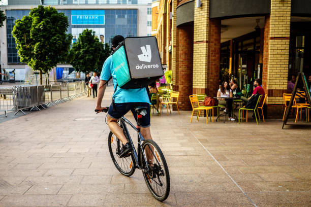 Deliveroo driver is riding in Coventry City Centre Coventry, UK - July 4, 2018: Deliveroo driver is riding in Coventry City Centre,  busiest time of the day evening for Delivery. west midlands photos stock pictures, royalty-free photos & images