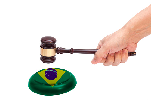 Hand knocking a Judge gavel at soundboard with Flag of Brazil Isolated on white background