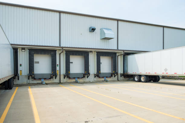 istock Warehouse building with 53 foot dry van trailers backed into docking doors 1034565800