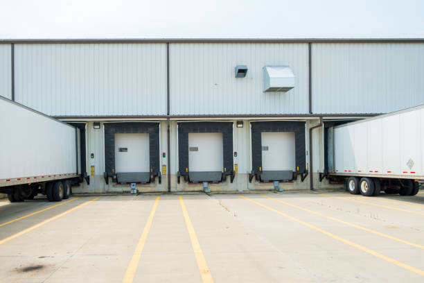 istock Warehouse building with 53 foot dry van trailers backed into docking doors 1034565804