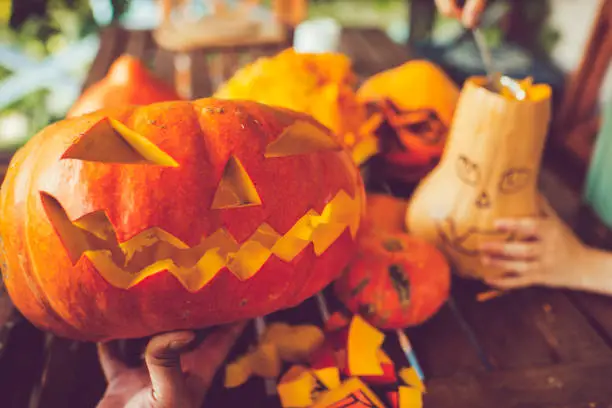 Man cutting spooky face on pumpkin in Halloween