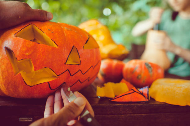 Man cutting spooky face on pumpkin in Halloween