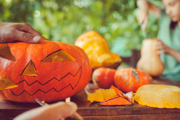 istock Man carving spooky face on a pumpkin in Halloween 1034566652