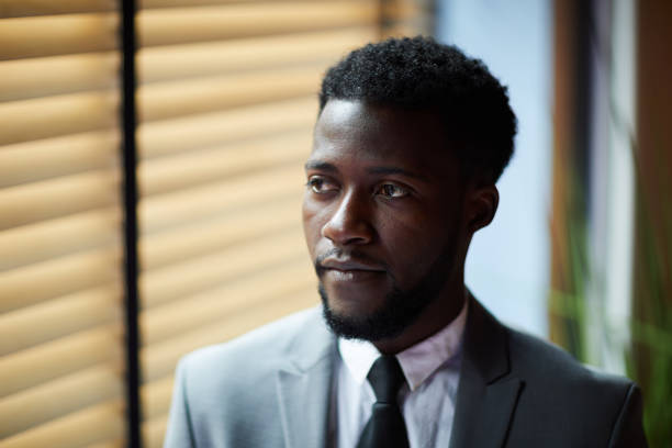 istock Serious contemplative black bearded businessman wearing formal suit looking away while standing in office corridor 1034581314
