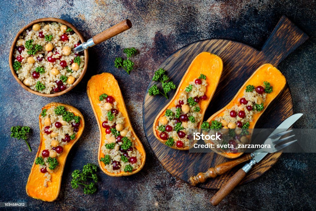 Stuffed butternut squash with chickpeas, cranberries, quinoa cooked in nutmeg, cloves, cinnamon. Thanksgiving dinner recipe. Vegan healthy seasonal fall or autumn food Autumn Stock Photo