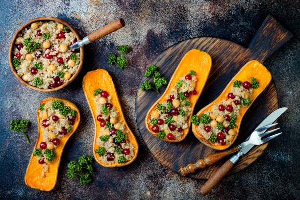 Stuffed butternut squash with chickpeas, cranberries, quinoa cooked in nutmeg, cloves, cinnamon. Thanksgiving dinner recipe. Vegan healthy seasonal fall or autumn food stock photo