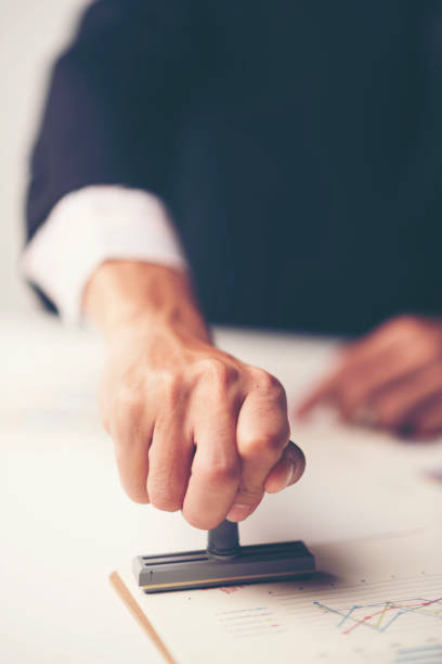 istock Close-up Of A Person's Hand Stamping With Approved Stamp On Document At Desk 1034587026