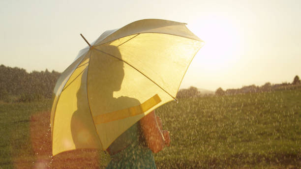 istock LENS FLARE: Cheerful young woman dances in rural setting in the spring rain. 1034600578