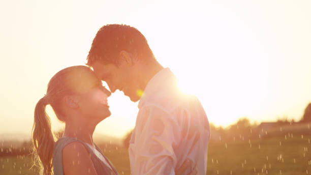 istock LENS FLARE Man gazes affectionately into woman's eyes while they dance in rain 1034600784