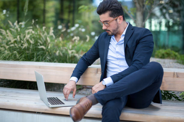 istock Handsome young businessman working outside on his laptop 1034603294