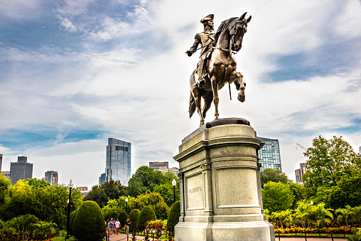 George Washington statue in Boston Common Park with city skyline and skyscrapers.