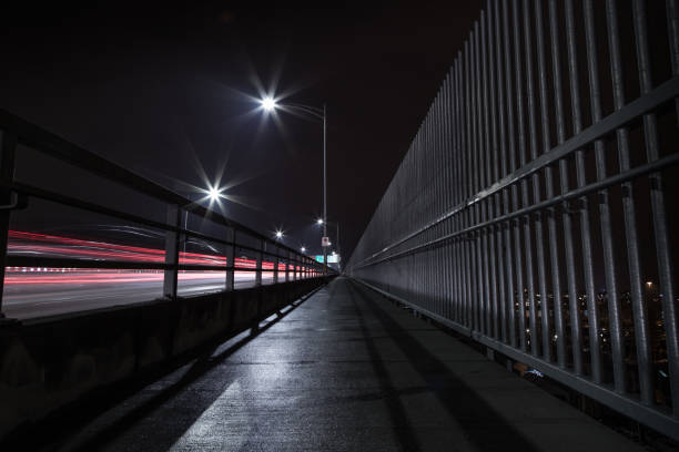 istock The Second Narrows Bridge sidewalk at night, with light trails from passing cars. 1034606358