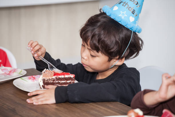 istock Little boy with hat eating birthday cake 1034606694