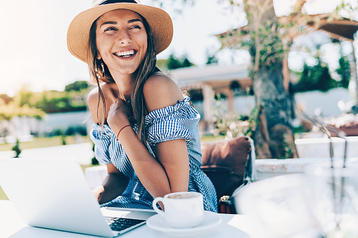 Beautiful young woman working on a laptop outdoors in the back yard