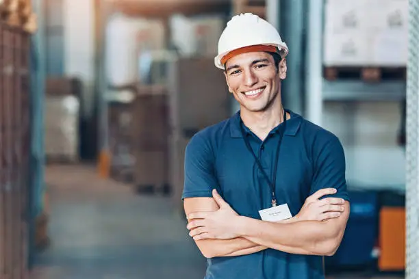 Portrait of a smiling young man with protective helmet in a warehouse