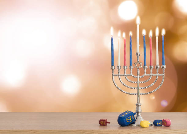 hanukkah fond fête juive avec la menorah (candélabre de judaïsme) brûlant des bougies et jouet jeu traditionnel dreidrel sur table en bois et flare de soleil automne bokeh - traditional culture flash photos et images de collection