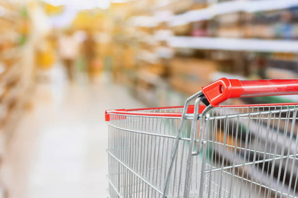istock Supermarket aisle blurred background with empty red shopping cart 1034620254