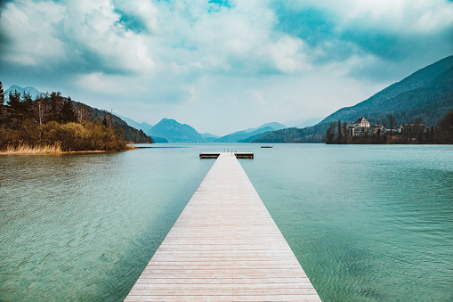 Scenic panorama view of an idyllic wooden landing stage on a beautiful lake in the Alps on a moody cloudy day in summer with retro vintage filter effect