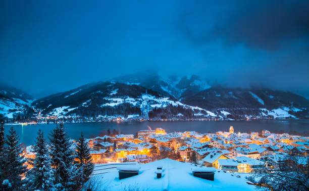 Zell am See in winter, Salzburger Land, Austria Panoramic view of Zell am See with Zeller See lake in twilight during blue hour at dusk in winter, Salzburger Land, Austria winter village austria tirol stock pictures, royalty-free photos & images