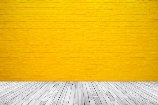 Yellow brick wall texture with wood floor background for pattern design.