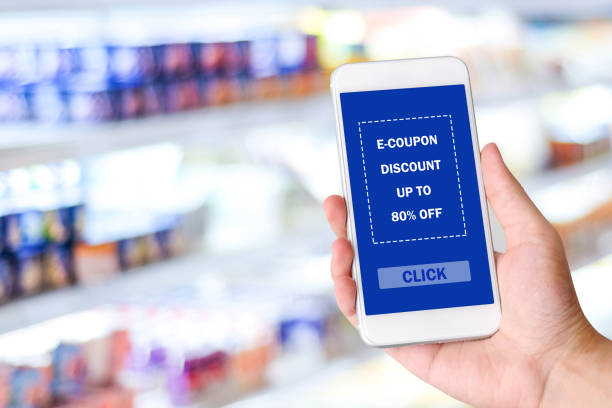 istock Hand holding smartphone with E-coupon, discount coupon on screen device over blur grocery background, shopping on line promotion, on line shopping, digital marketing, business and technology concept 1034691674