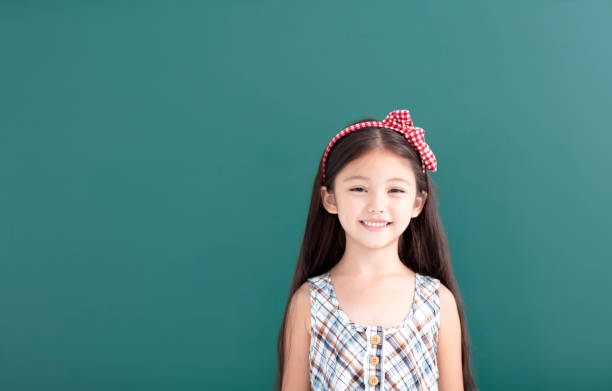 istock smiling little girl stand before empty chalkboard 1034697366