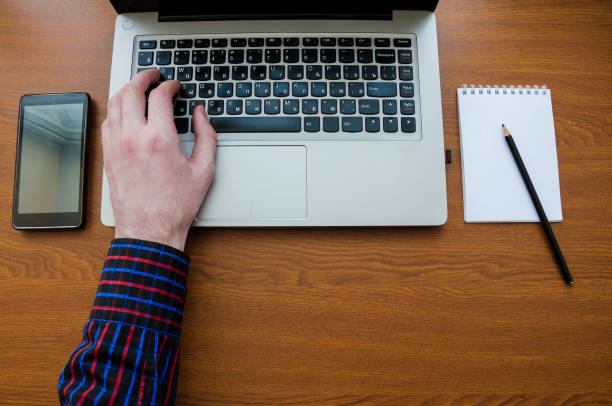 istock Business man using laptop computer hand typing on laptop keyboard with notebook pen glasses and cup of hot coffee 1034700048