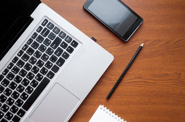 istock Wood office desk table with laptop, glasses, notebook, pen, smartphone. Top view, copy space. 1034700066