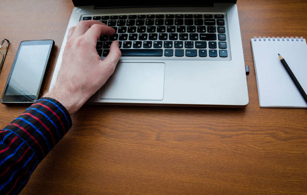 istock Business man using laptop computer hand typing on laptop keyboard with notebook pen glasses and cup of hot coffee 1034702428